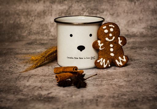 A beautiful shot of a mug, Christmas cookie and a cinnamon on a grayish surface - Xmas background