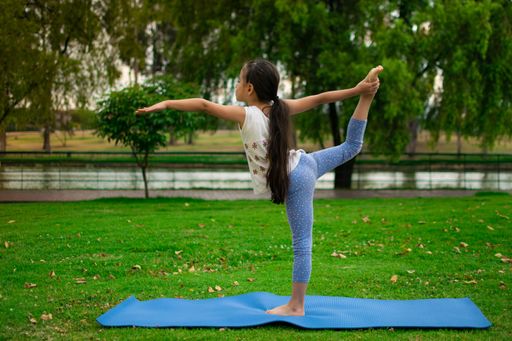 A closeup shot of a cute Latin girl practicing yoga in a park