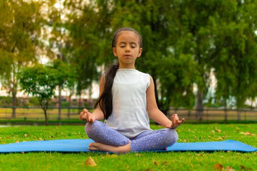 A closeup shot of a cute Latin girl practicing yoga in a park