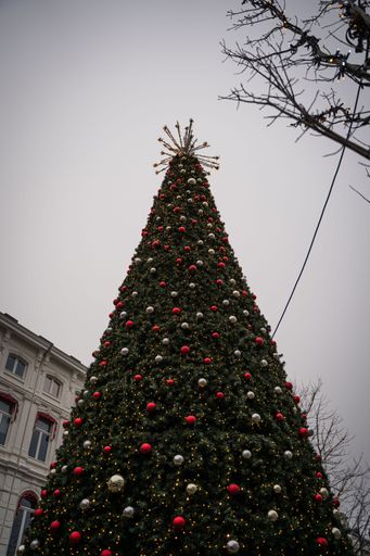 A vertical low angle shot of a Christmas tree decorated with Christmas baubles