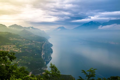 A foggy morning view at Largo di Garda, Italy with green hills near the water