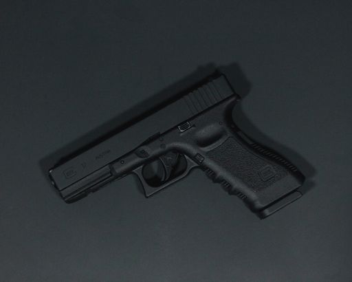 A top view of a handgun on a gray surface under the lights