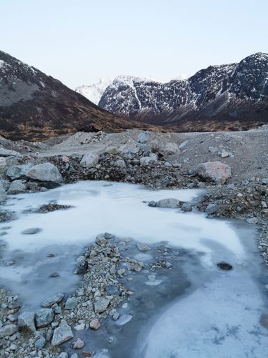 A rocky lakeshore and mountain landscape during winter in the Island of Kvaloya in Tromso, Norway