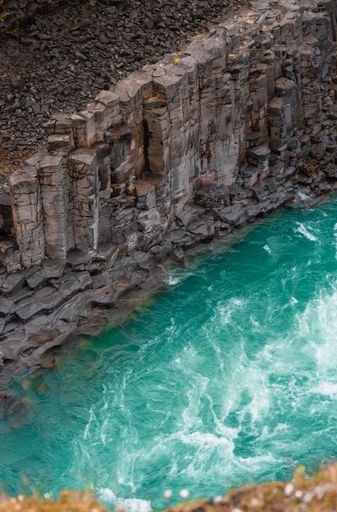 A vertical aerial shot of rocks near a an ocean with ocean blue waves