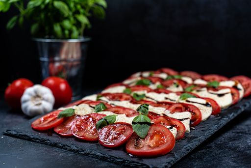 A close-up shot of a caprese, Italian food served on a table with a dark background