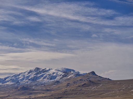 A beautiful view of a snow-capped mountain under a blue sky with clouds.