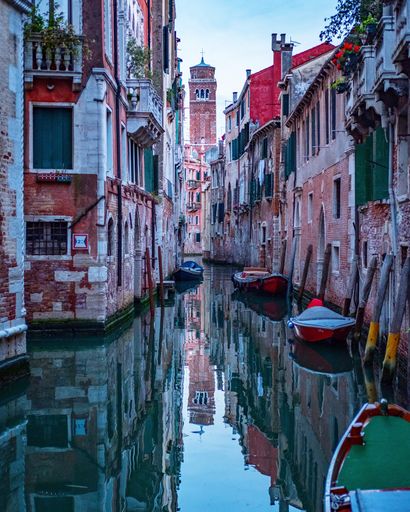 A beautiful shot of Venice with colorful buildings and boats reflected in the canal
