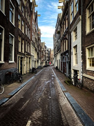 A vertical shot of an empty street surrounded by buildings in Amsterdam