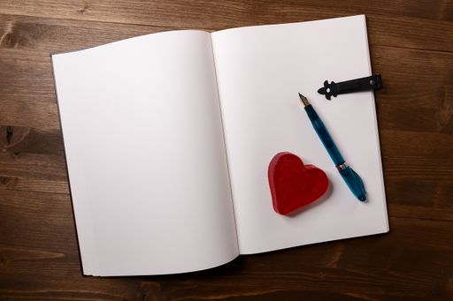 A high angle shot of a small Valentine's day notebook with a pen on a wooden table