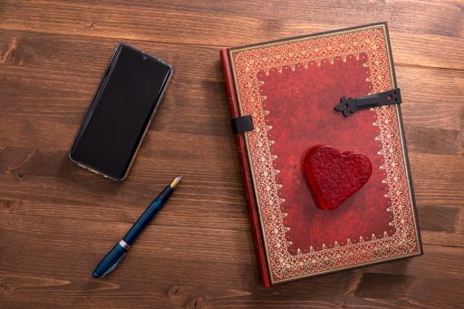 A high angle shot of a small Valentine's day notebook with a pen on a wooden table