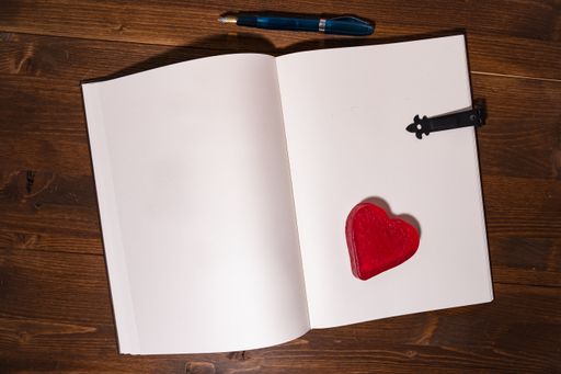 A high angle shot of a small Valentine's day notebook with a pen on a wooden table