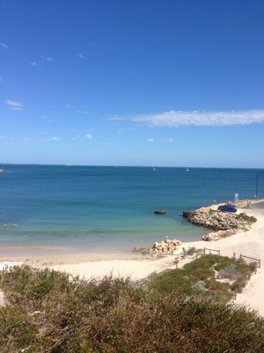 A vertical shot of a sandy beach with a calm sea captured on a clear, sunny day