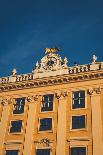 A modern building with large windows and a prominent clock tower topped with a golden bird statue