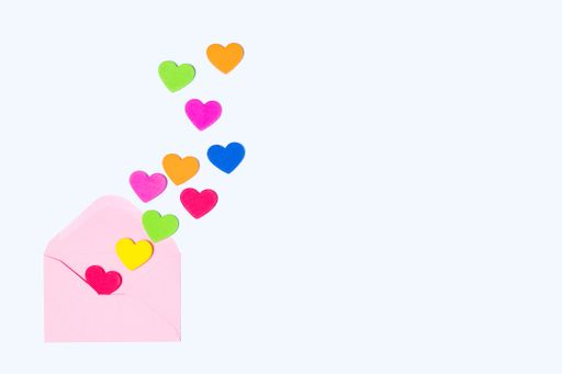 Colorful hearts emerging from a pink envelope on a light blue background. Copy space for text