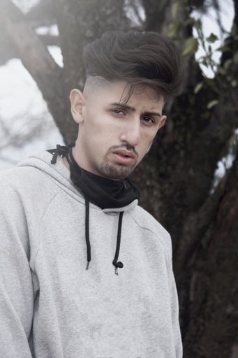 A vertical shot of a young Latin man with a stylish haircut and casual clothes