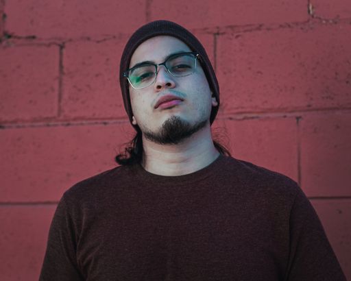 A selective focus shot of a handsome caucasian male in glasses posing near a brick wall