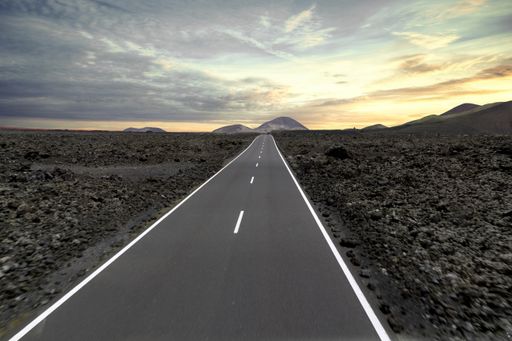 A road surrounded by hills and stones during the sunset in the Timanfaya National Park in Spain