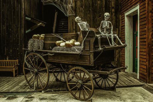 An old wooden carriage with skeletons and pumpkins on it in a building