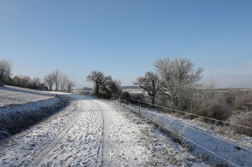 A winter landscape of car trails on snowy fields under a cloudy blue sky