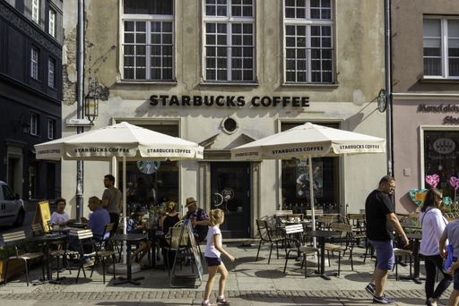 Starbucks cafe terrace with gray umbrella in the center of the Gdansk. People drink coffe and capuccino on the street.