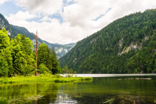 The Lake Toplitz in Austria surrounded by green hills under the cloudy sky
