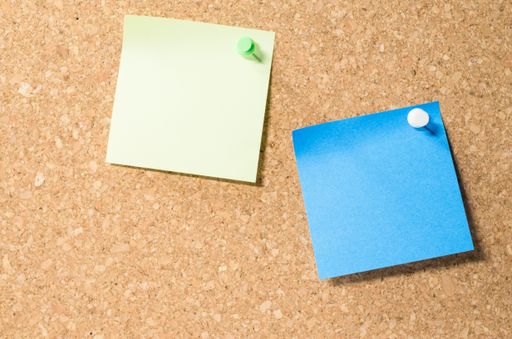 A view of two blank post-it notes on a corkboard with copy space