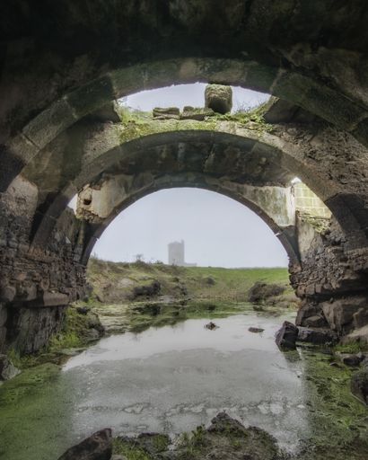 A vertical shot of an old stone bridge over a river