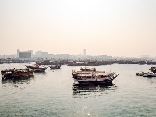 A beautiful view of traditional dhow boats moored in the port near Museum of Islamic Art Park at sunset