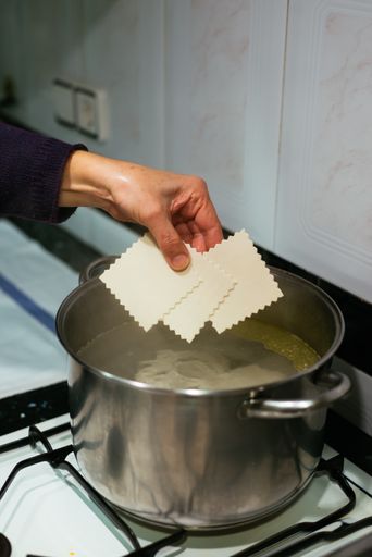A selective focus shot of a woman cooking Cannellonis in the kitchen