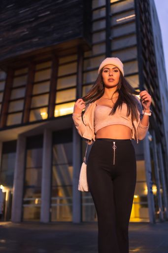 A low angle shot of a young pretty caucasian female in a pink hat and short top posing for the camera