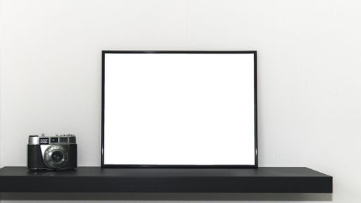 A white board with space for text and a photo camera on a shelf