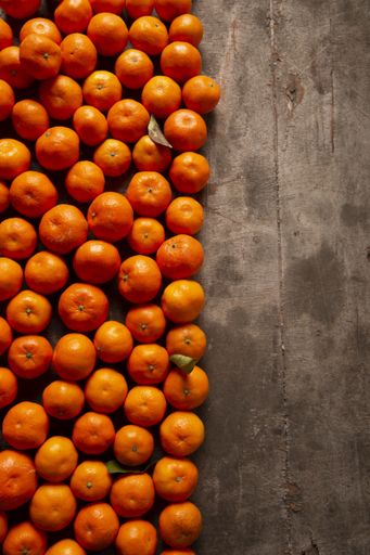 A vertical shot of fresh ripe tangerines on wooden background with space for text