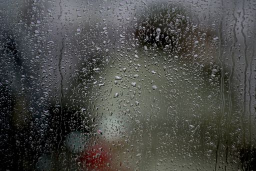 A window with raindrops on it under the lights with a blurred background