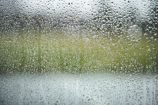 A window with raindrops on it under the lights with a blurred background
