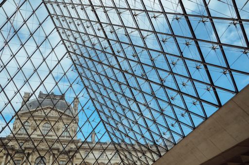The Louvre Museum surrounded by buildings under a blue sky and sunlight in Paris in France