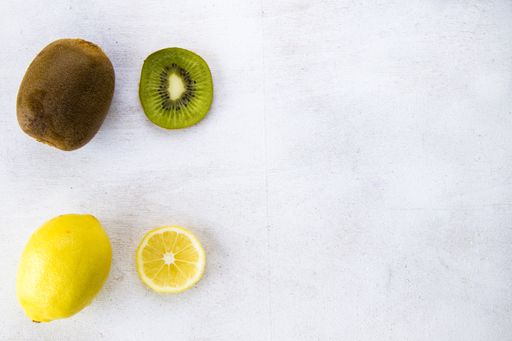 An overhead shot of c lemon and kiwi on the left side of the white background