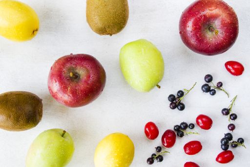 a top view of Currant, Cornus and dogberry, lemon, apple and kiwi on white background