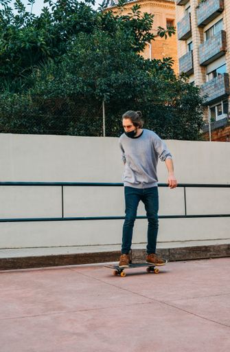 Picture of Vertical Shot of Male Skater with Black Face Mask Skateboarding in a Park Track.