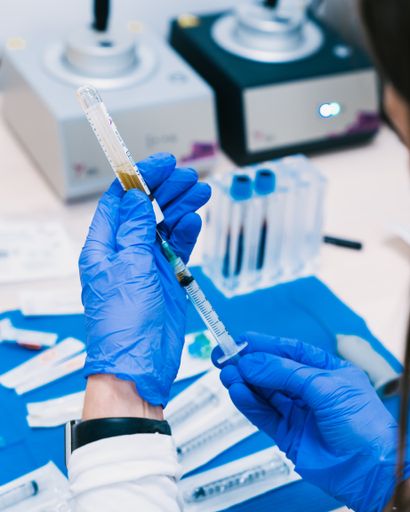 A vertical shot of a doctor with medical gloves holding medicine liquid vaccine vial bottle and syringe - COVID-19 vaccination
