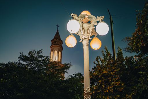 A low angle of a lantern against green treetops and a chapel dome on the street in El Fuerte, Sinaloa, Mexico