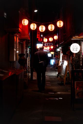 A dramatic scene of an alley in Japan red light district at night, illuminated by lanterns