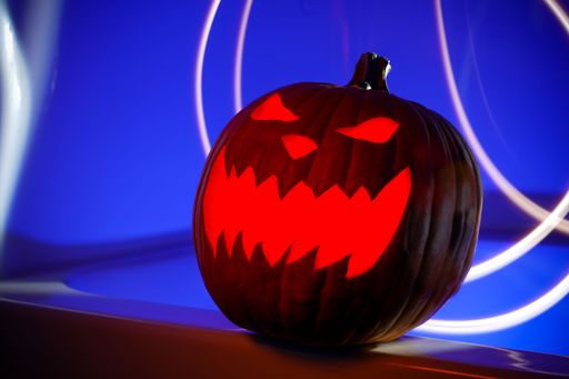 A closeup shot of a glowing red jack-o-lantern on a blue background