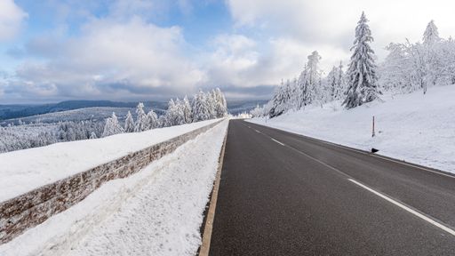 A beautiful shot of a road leading through snowy trees in the Black Forest mountains of Germany