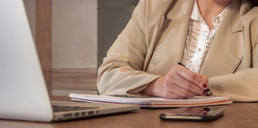 A selective focus shot of a young businesswoman writing in her notepad