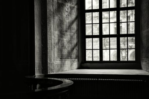 An inside view of a vintage window in the cathedral, sunbeams falling into the dark space