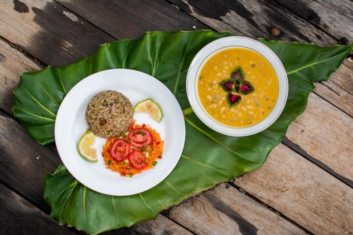 A bowl of pumpkin soup and a plate of a cutlet served with vegetables on a decorative green leaf