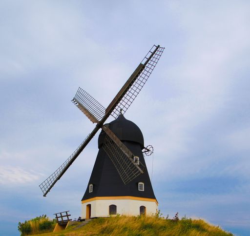 A beautiful scene of the windmill in the field with yellow grass on the blue sky background