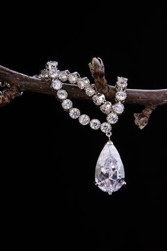A vertical closeup of a beautiful necklace on a branch isolated on black background.