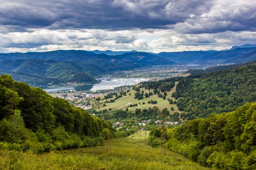 A stunning aerial view of a picturesque valley, with immaculate rolling green hills, surrounded by towering snow-capped mountains