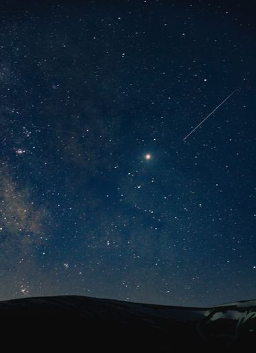 A beautiful shot of an amazing sky full of breathtaking stars at night over the hills in the countryside